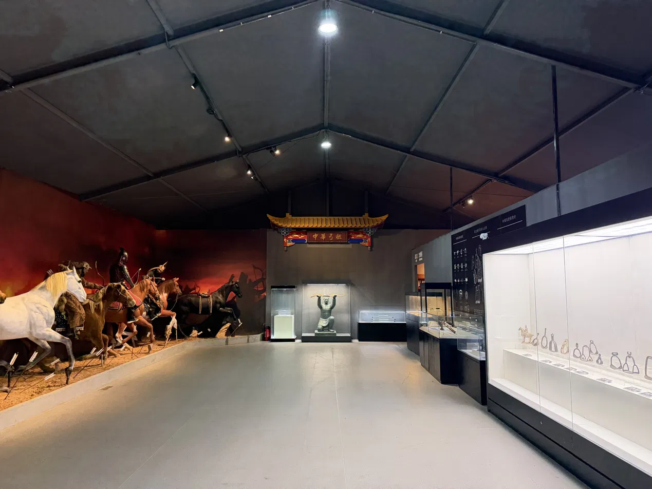 An exhibition hall with mounted archer figures and cases of archery equipment