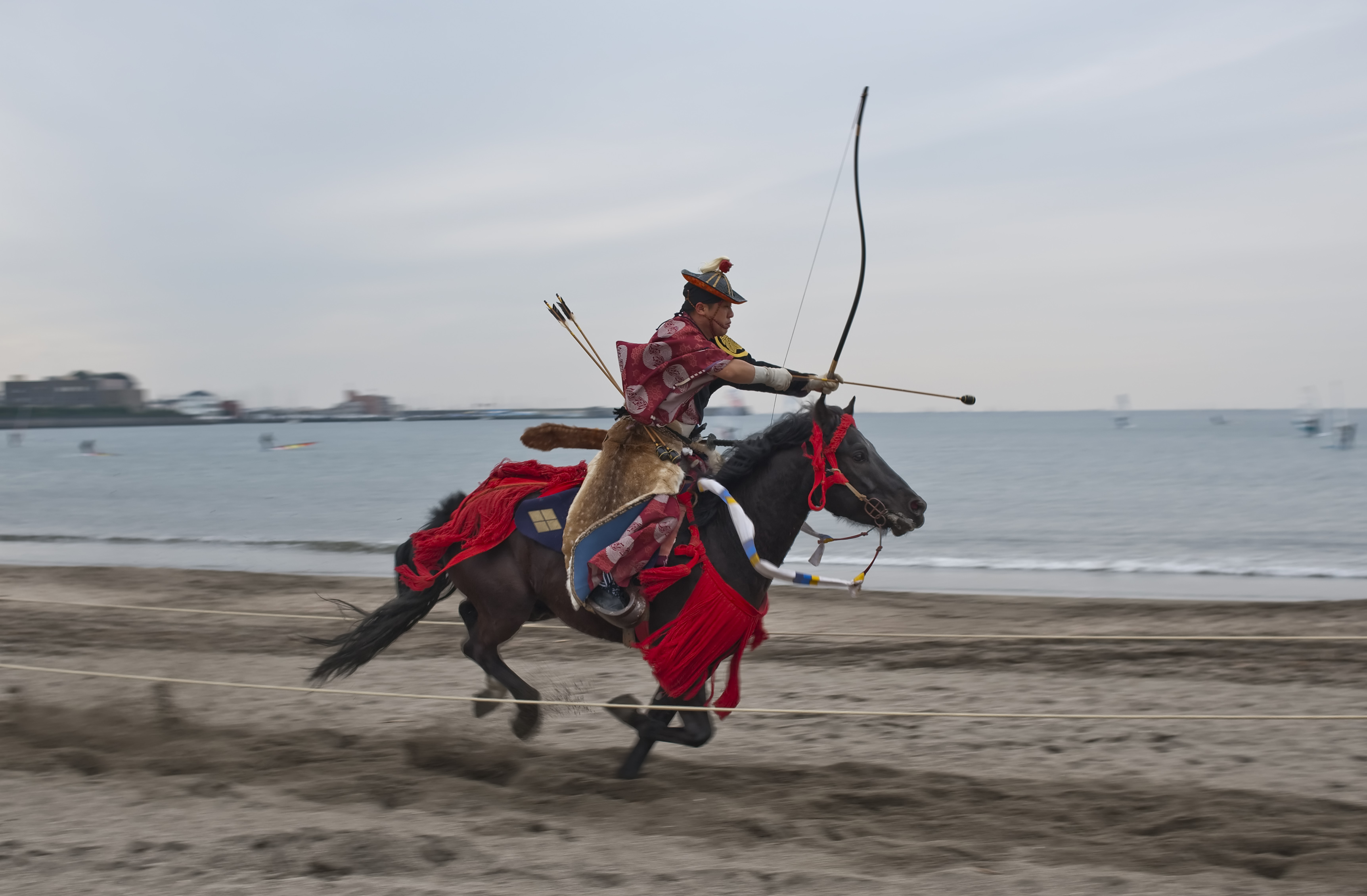 A yabusame rider drawing a traditional bow on horseback in Zushi